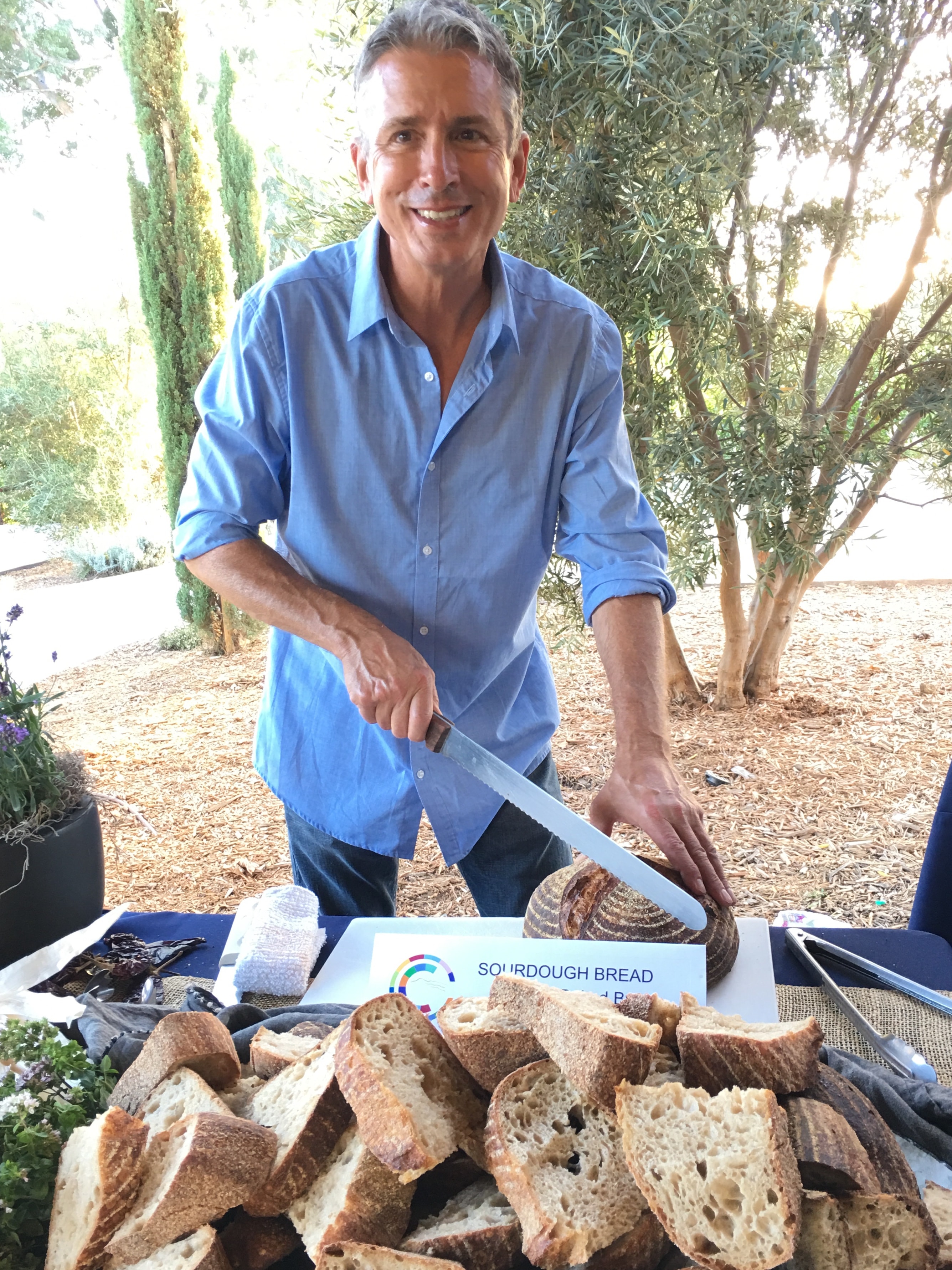 Claud cutting sourdough bread at an outdoor event