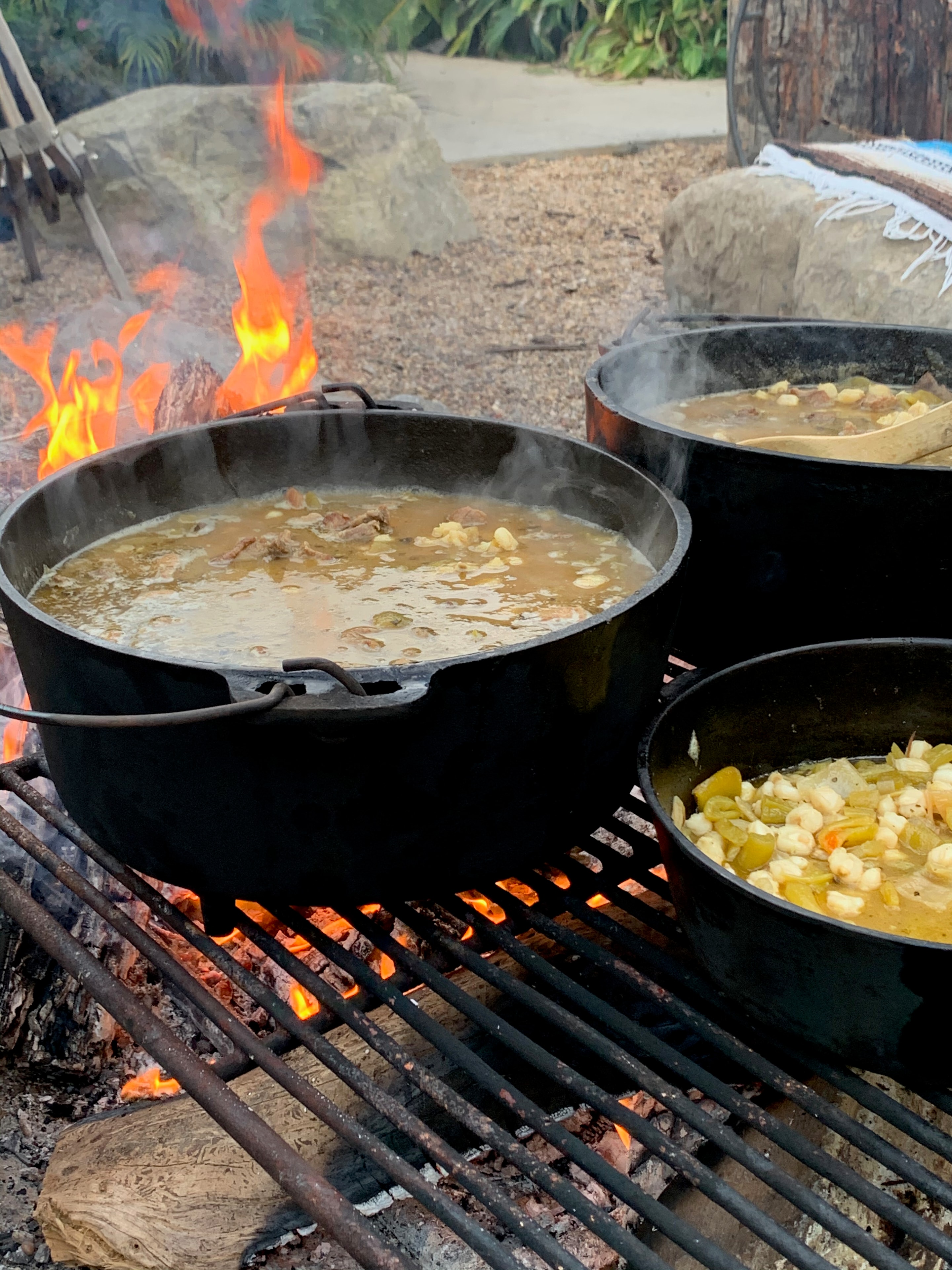 Pots of stew cooking over an open campfire