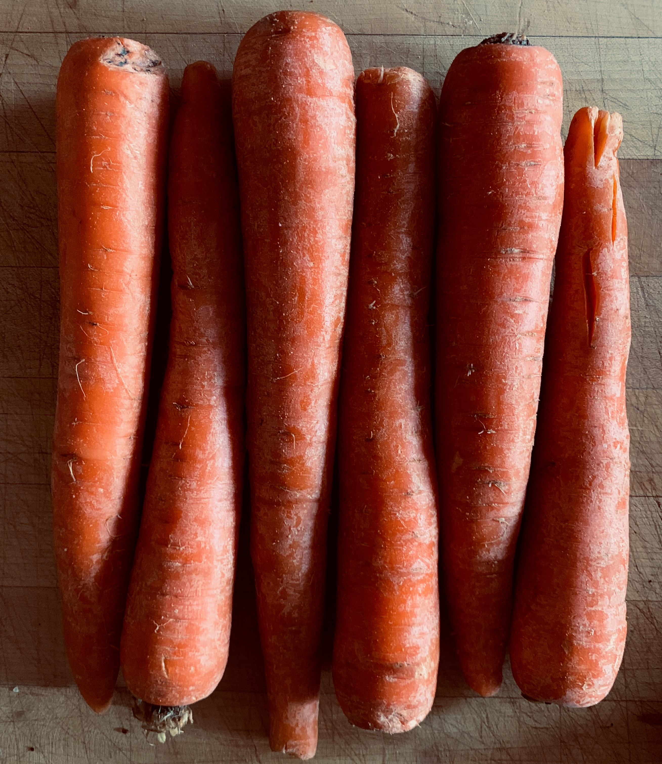Fresh carrots laid out on a wooden cutting board