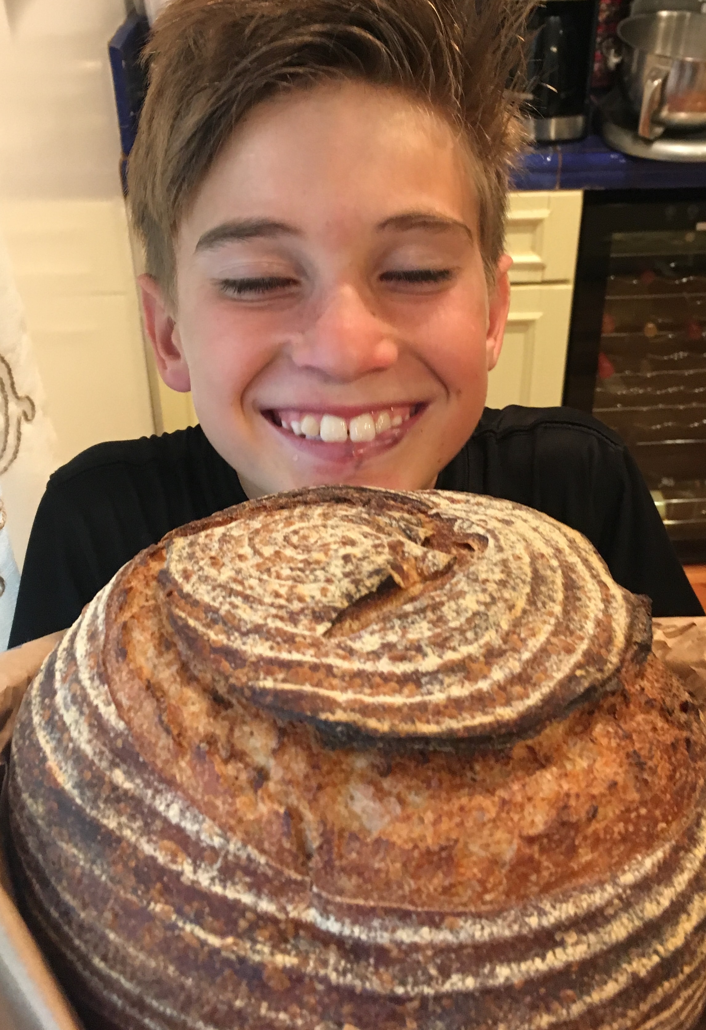 A child beaming over a freshly baked sourdough boule